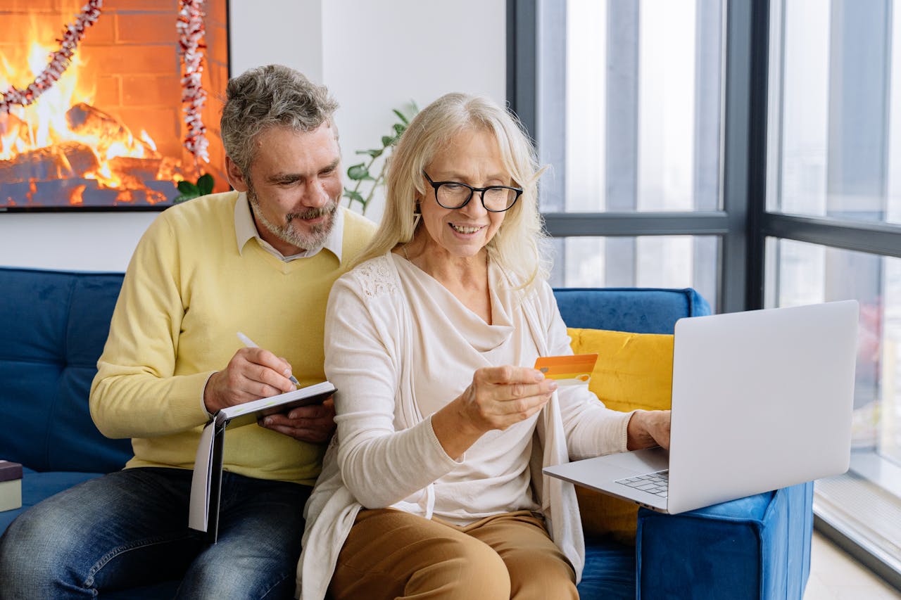 Senior couple shopping online together using a laptop indoors, embracing technology.